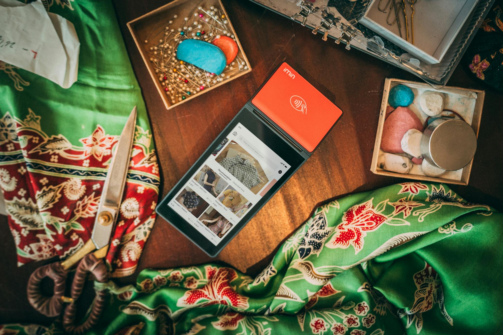 Flat lay of fabrics, sewing tools, and digital tablet showcasing a creative design workspace.